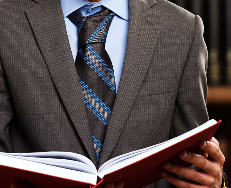 A man in suit and tie holding an open book.